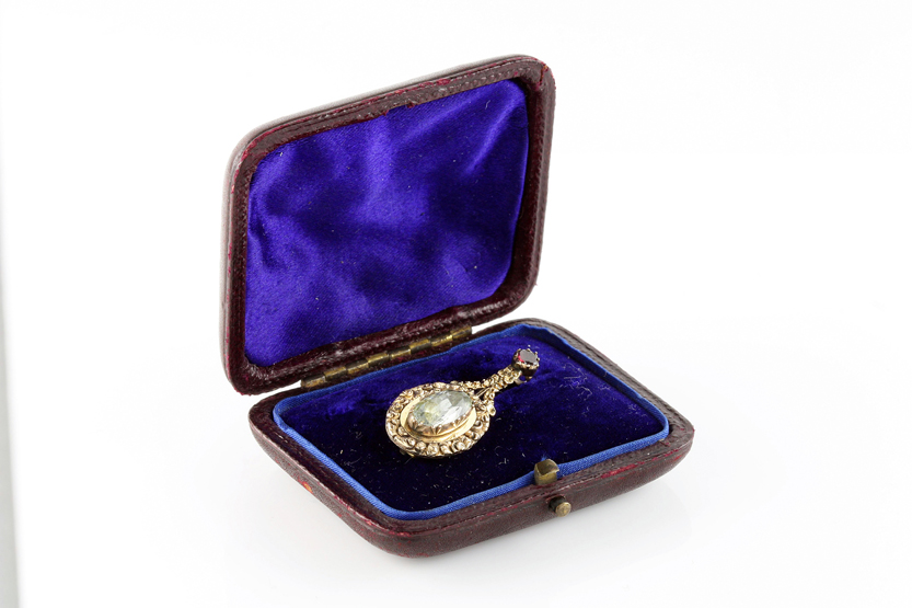 A Georgian pear shaped brooch set with foiled peridot stone surmounted by an almadene garnet, in