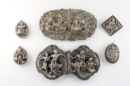 A collection of Indian white metal objects, including two heavily embossed belt buckles, a square