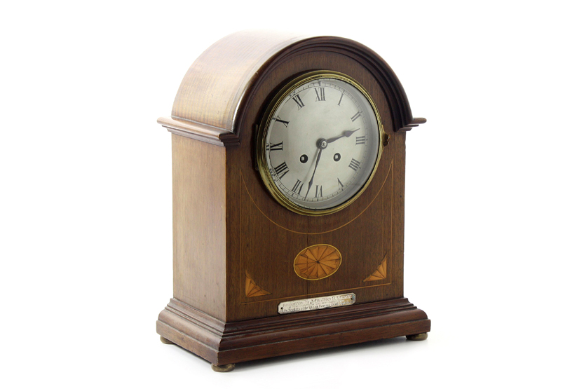 An Edwardian mahogany cased mantel clock, the domed top case with satinwood inlay, with silvered