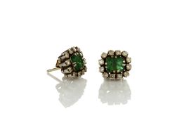 A pair of white metal earrings set with centre emeralds set by small diamonds, in claw setting