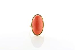 An oval coral ring, set in unmarked yellow metal, probably 9ct gold