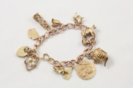 A 9ct gold curb link charm bracelet on padlock clasp with 11 charms including a teapot, a bell, a St