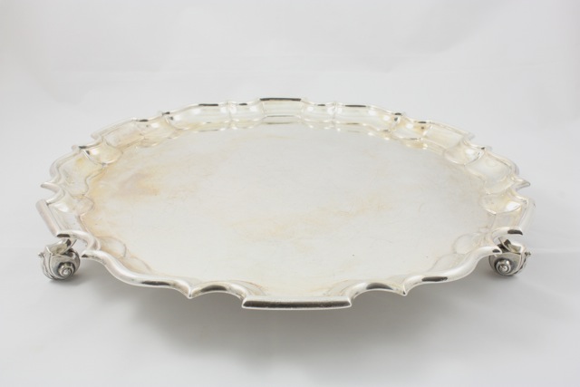 A silver tray hallmarked London, 1904/5, with pie crust border, raised on three scroll feet, with
