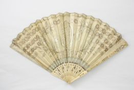 An early 19th century ivory and silk fan with ivory sticks pierced with flower heads and foliage,