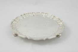 A small silver waiter London 1904/05, with pie crust border and three scroll feet, length 16.5cm