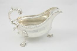 A George III style silver sauce boat London 1904/05, with high scroll handle, gadrooned rim,