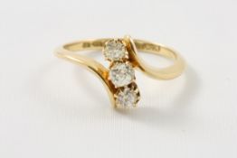 An 18ct gold three stone diamond ring probably 1930s, claw set diamonds in swirl setting Ring size K