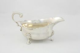 A George III style sauce boat hallmarked London 1938/39, with C scroll handle, shaped rim, raised on