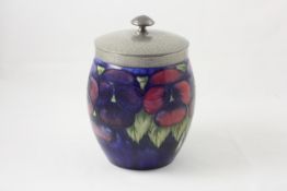 A Moorcroft `Pansy` biscuit barrel circa 1920, with tube lined pansy decoration on blue ground,