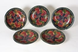 Five Moorcroft pottery `Pomegranate` plates circa 1920, on mottled green ground, with green