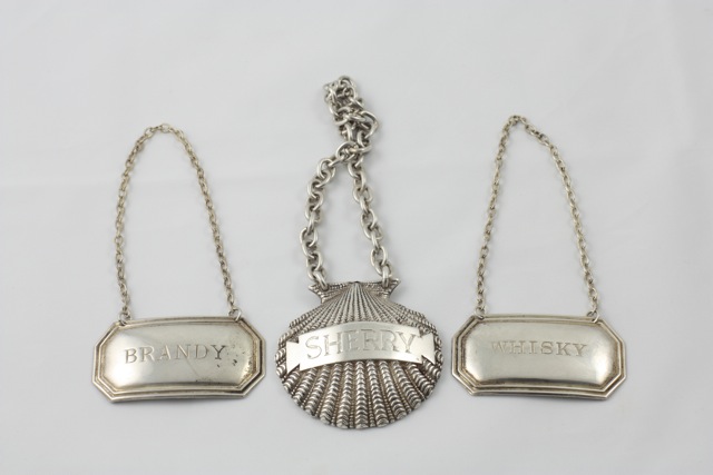 Three silver liquor labels comprising a SHERRY label in the form of a shell on a link chain
