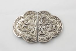 A Chinese silver coloured metal buckle 1900s, with repousse decoration of dragons, framed with