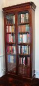 A Victorian mahogany two door bookcase circa 1870, the rounded cushion top above two long glazed