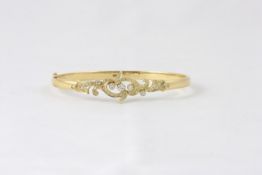 An 18ct gold stiff bangle Modern, set with numerous small diamonds in swirl shaped setting, with