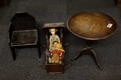 A Victorian dolls tilt top table, a rocking crib, chair and three dolls.