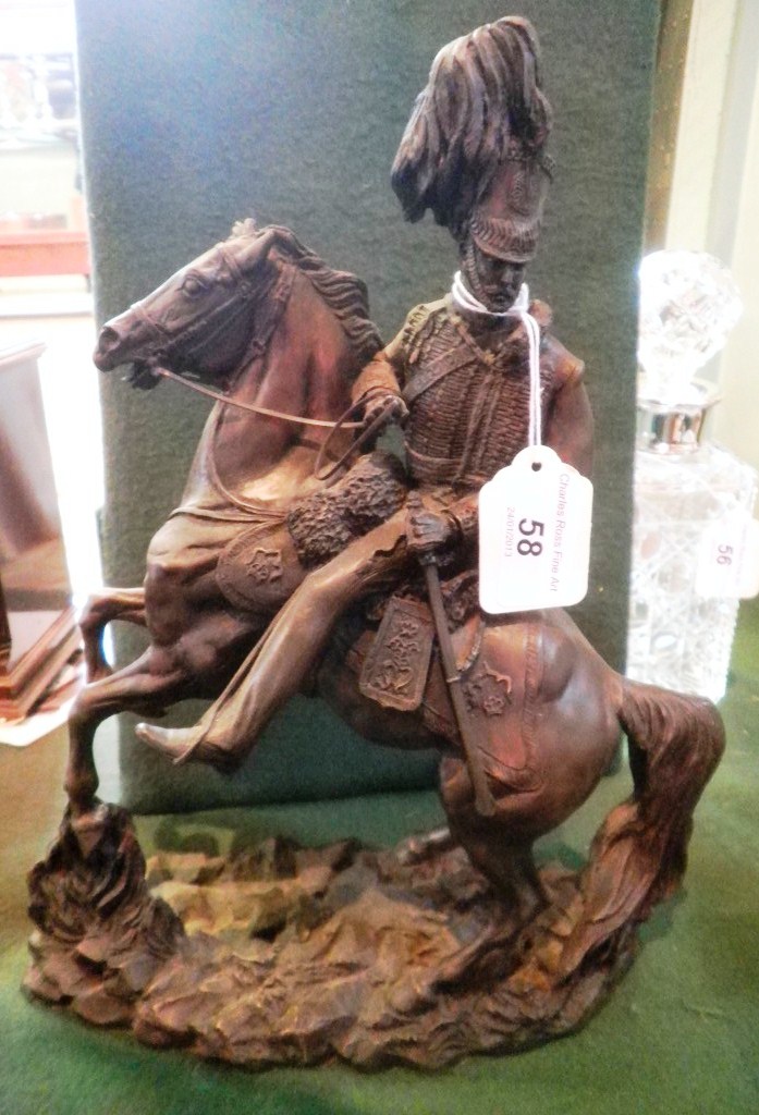 A moulded resin model of a cavalry officer with plumed helmet on rearing horse and naturalistic