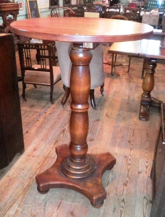 A 20th century pub table, having circular top, baluster column on concave plateau and bun feet.