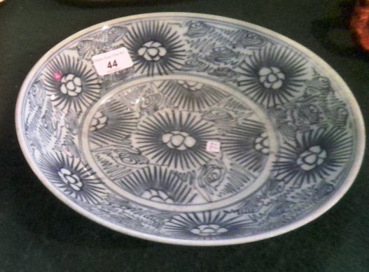 A tin glazed earthenware 27cm diameter dish, hand decorated in underglaze blue with stylized