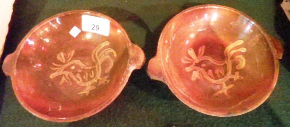 A pair of stoneware twin handled dishes, each slip decorated with a cockerel, 16cm diameter.