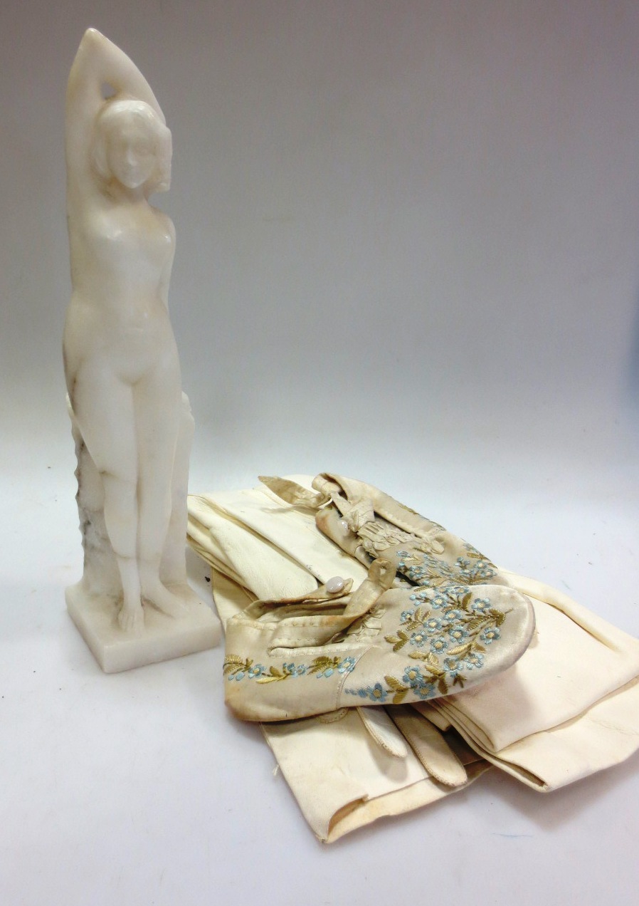 An alabaster nude, kid gloves and a pair of child`s embroidered slippers An alabaster nude, kid