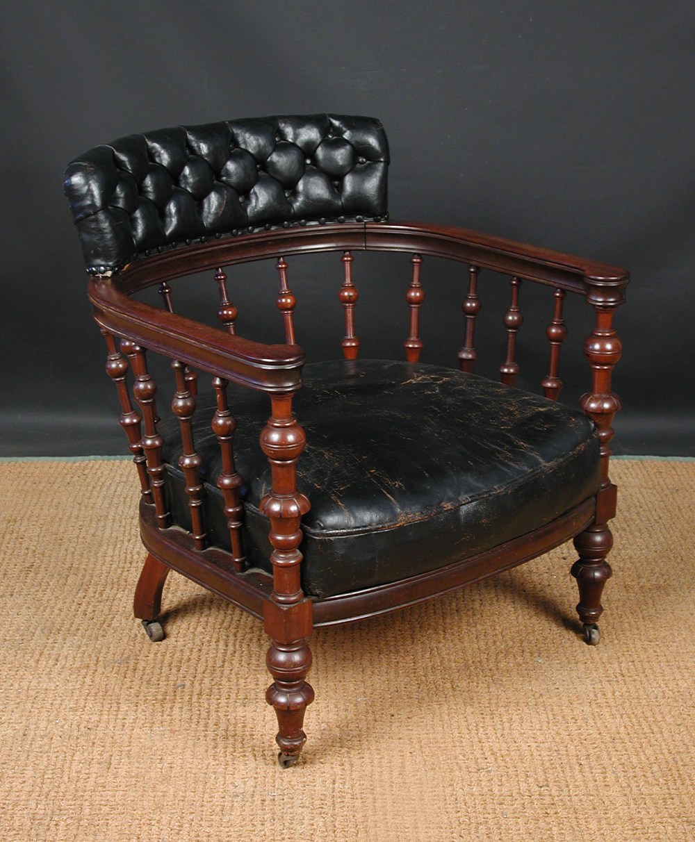 A late 19th century leather upholstered library chair, spindle gallery bow back with studded leather