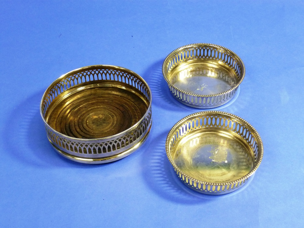 A silver plated Bottle Coaster, with pierced gallery and turned wood base, 5½in (14cm) diameter,
