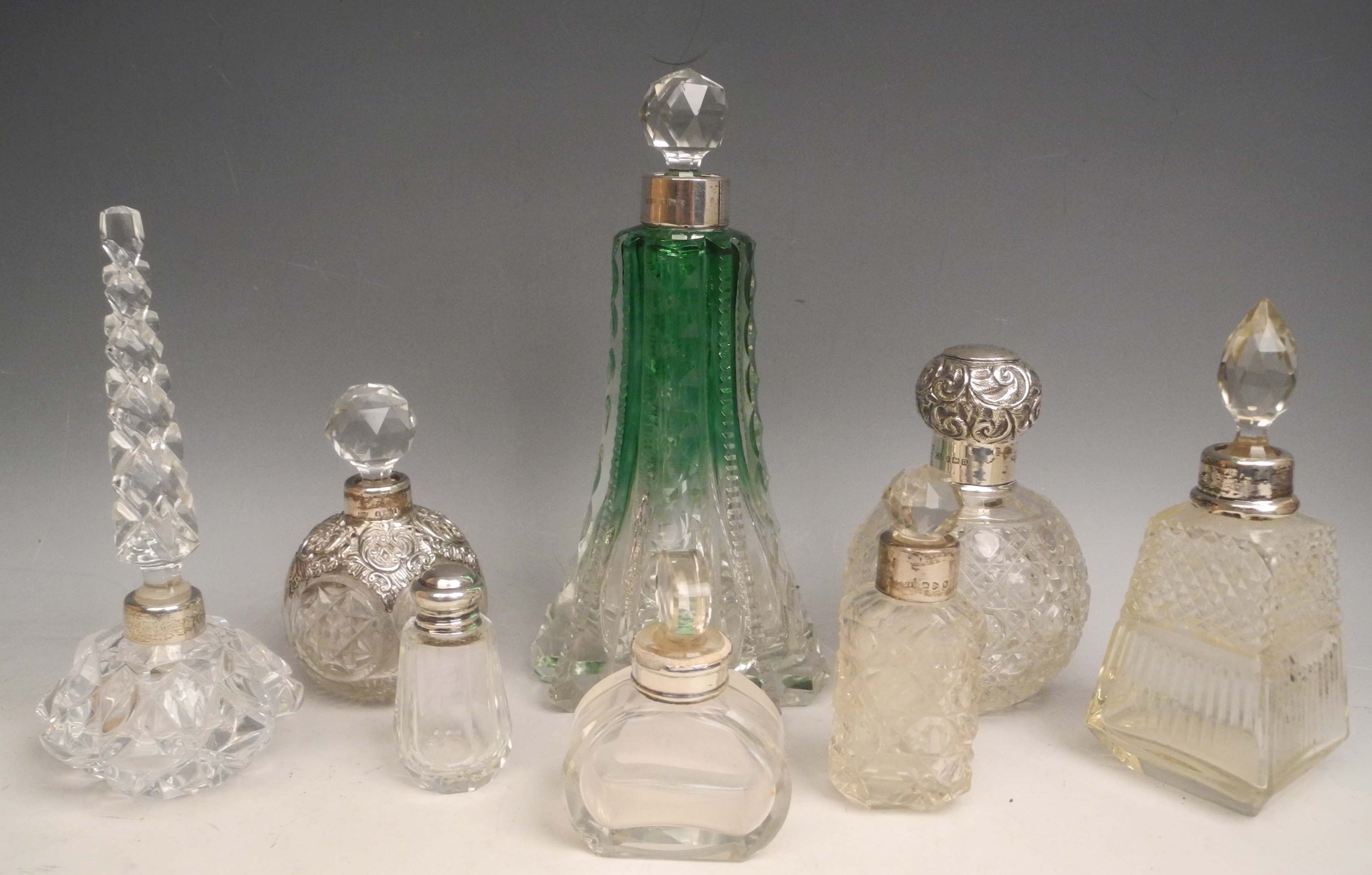 A collection of white metal necked perfume flasks, including a clear/green example. (8)