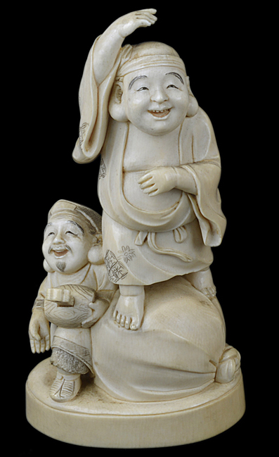 A 19th Century Japanese carved ivory okimono group of a deity standing on a sack, and his helper