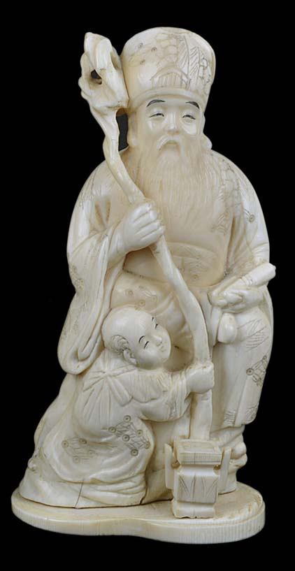 A Japanese 19th Century ivory carving of a seated lohan holding a staff, with a child at his feet.