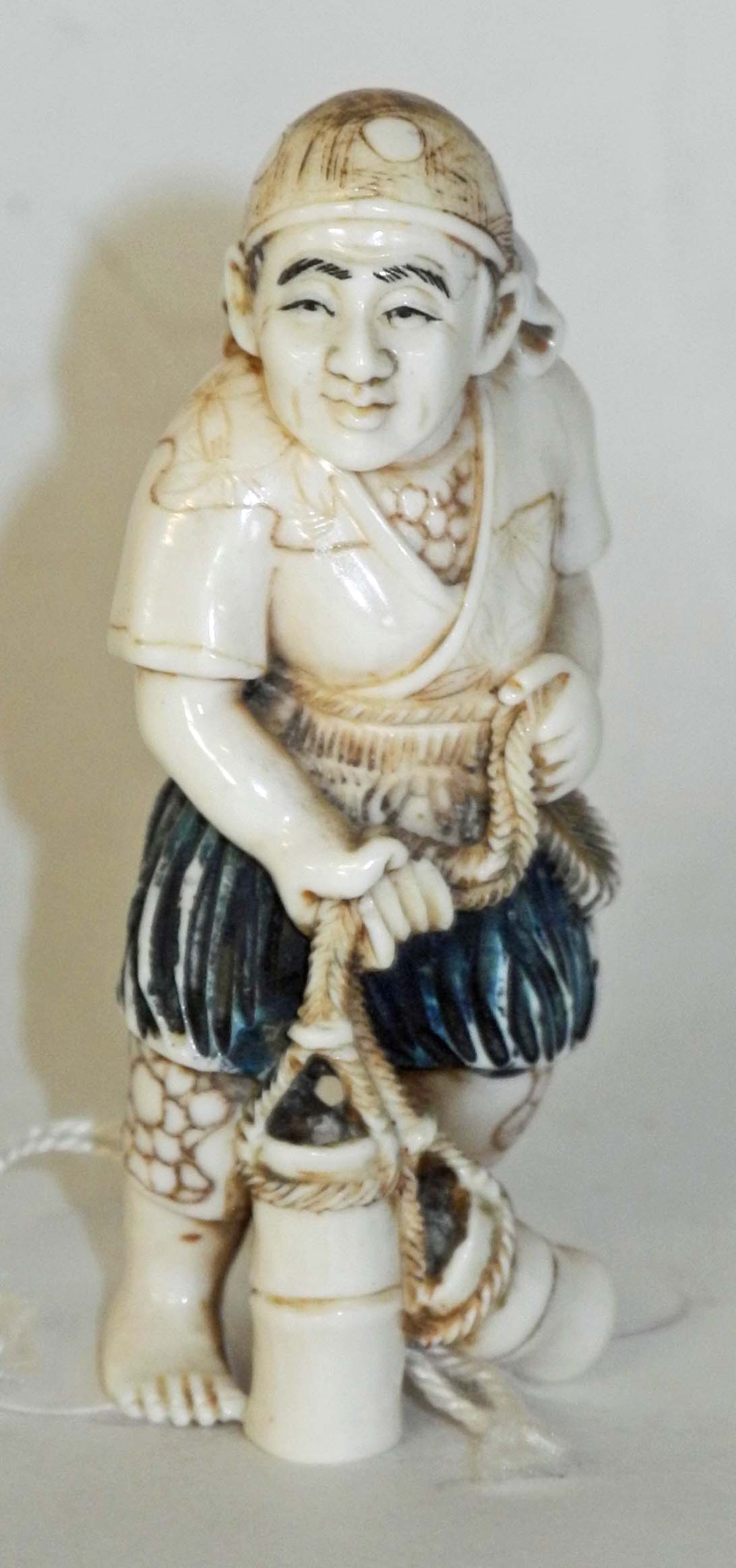 An antique ivory netsuke of a man carrying water containers, signed.6cm