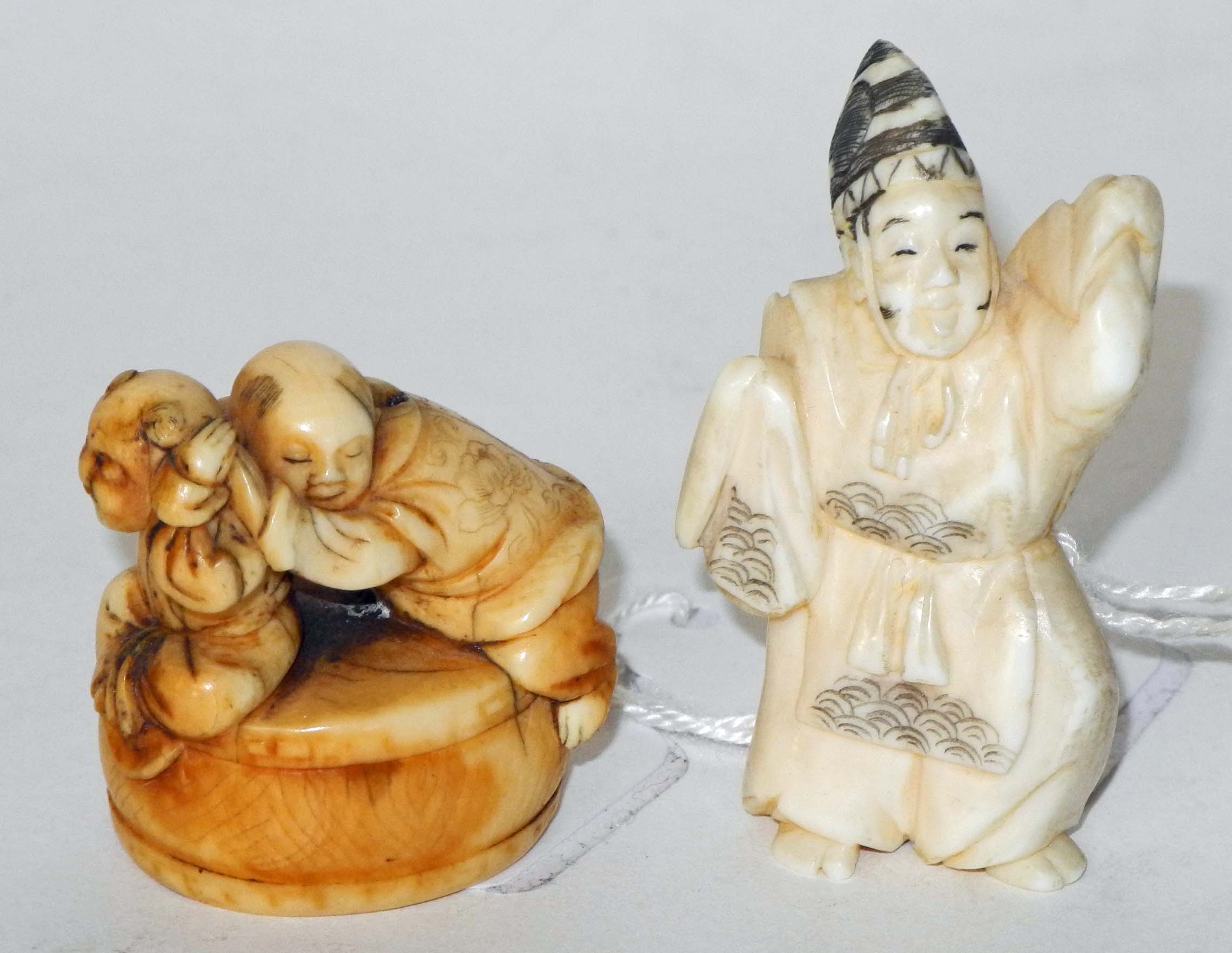 An antique ivory netsuke of two children, holding each others` ears, together with another of a