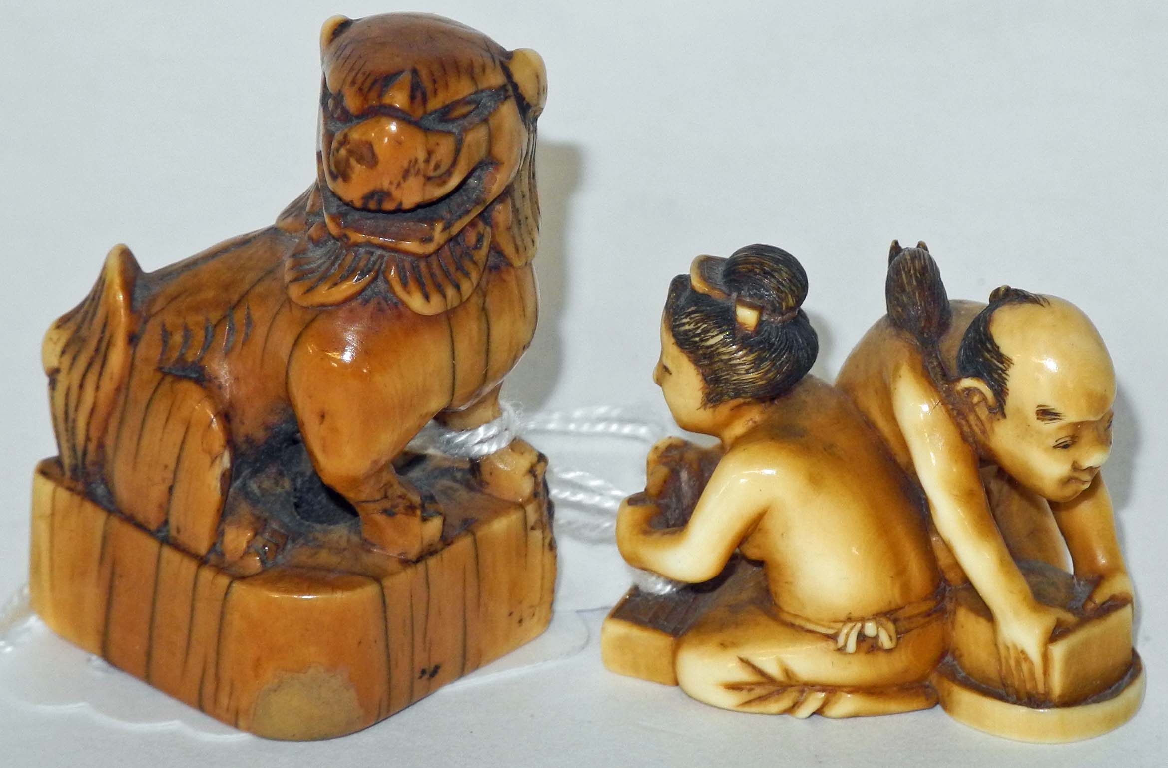 A Japanese ivory netsuke of two seated figures opposing each other with a rat on one`s back, signed,