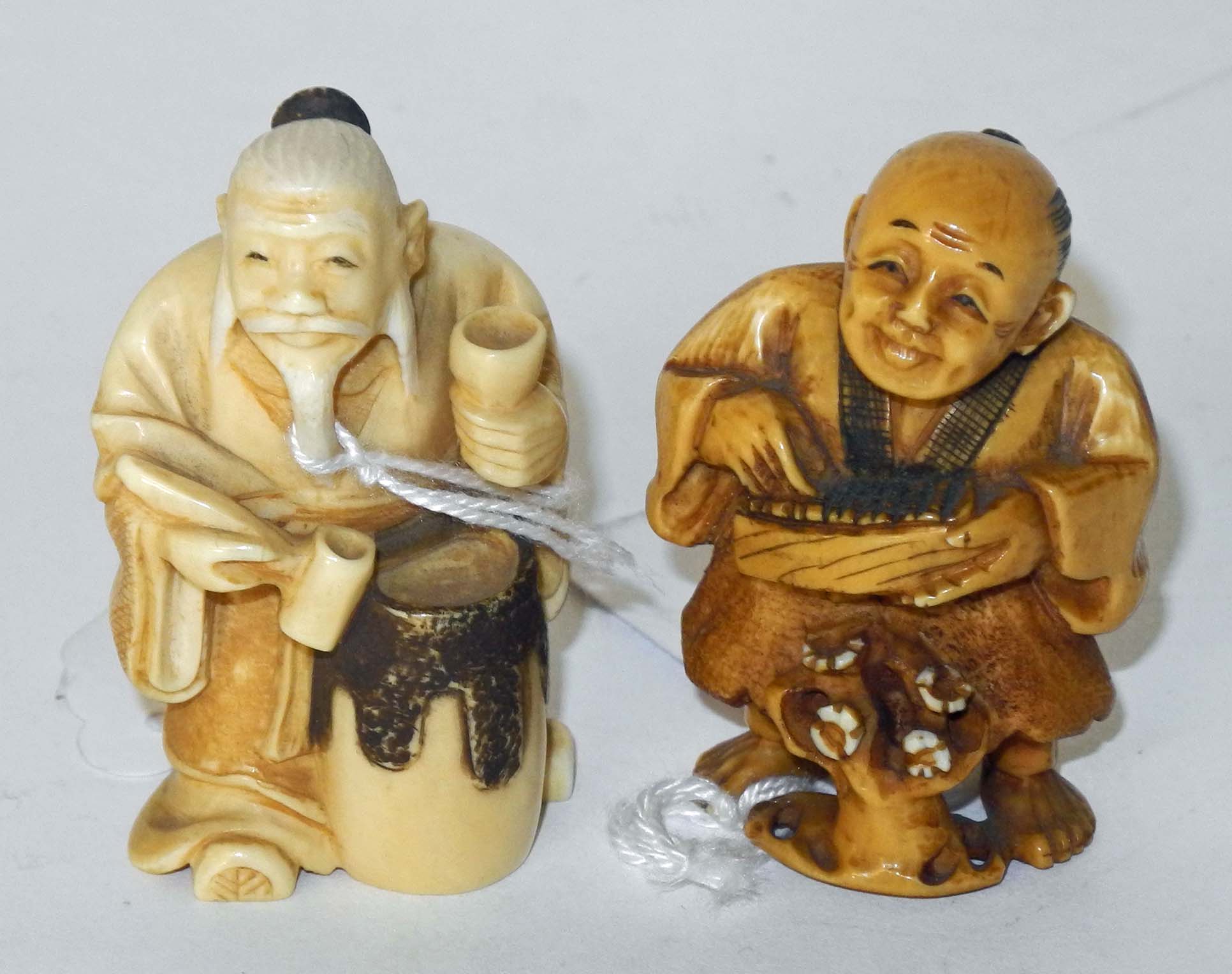 A Japanese ivory netsuke of an old seated man with beard, holding a sake cup, signed, together