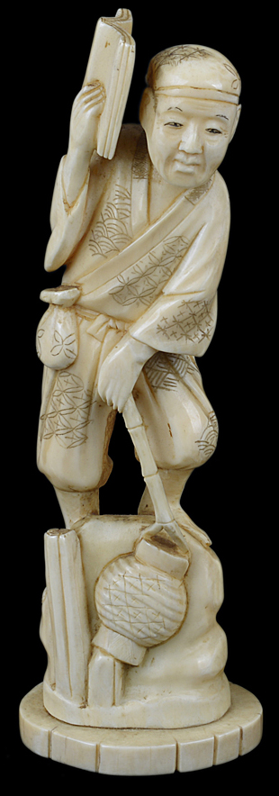 A late 19th/early 20th Century Japanese carved ivory figure of a man carrying a book and signed on