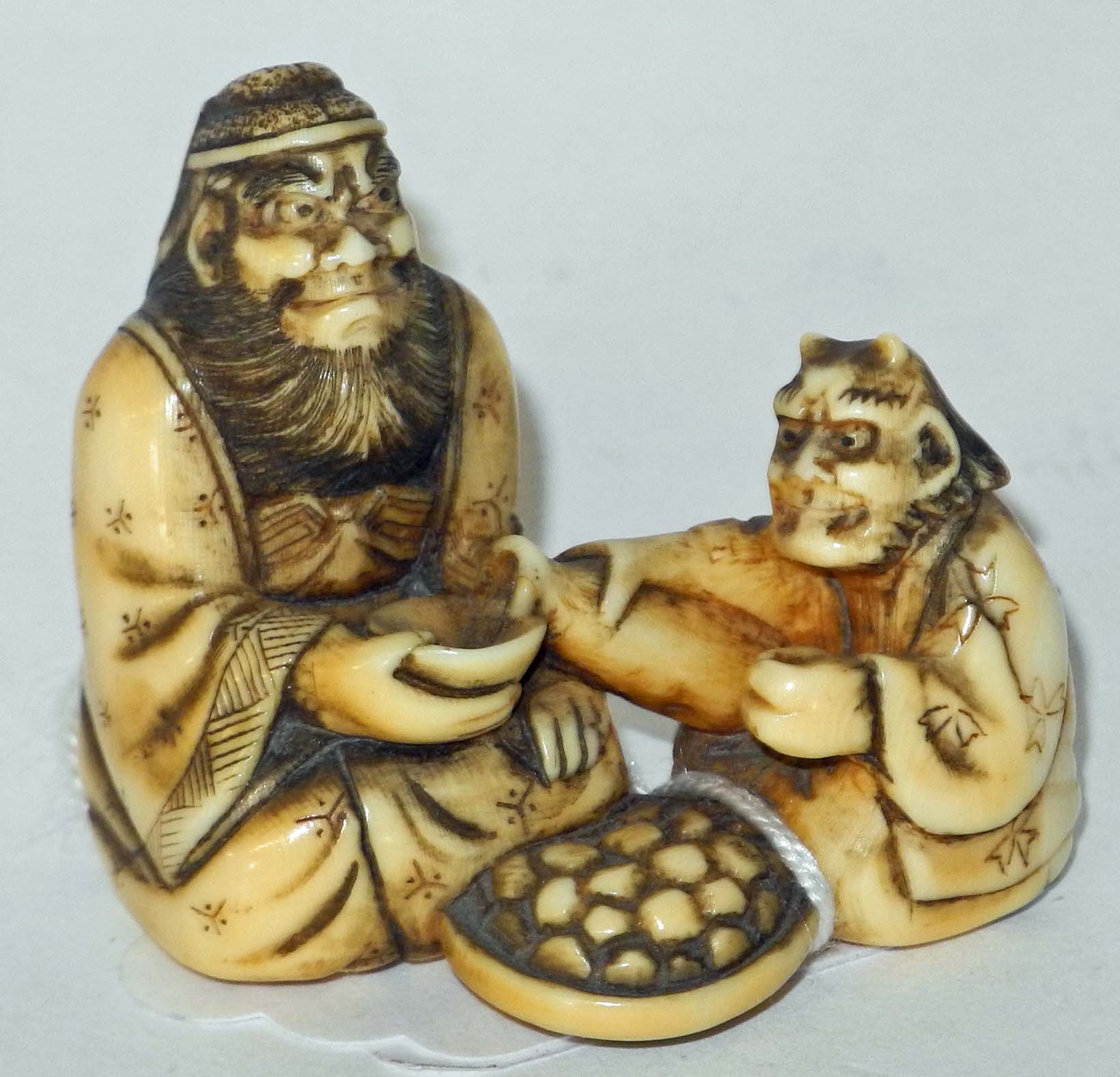 A Japanese ivory netsuke of two oni, one pouring a drink.3.5cm