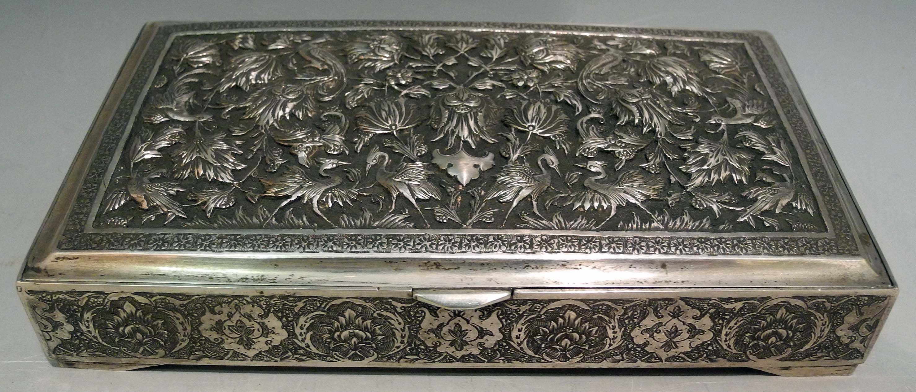 A Persian silver casket, the hinged lid top decorated in relief with birds amongst blooms.