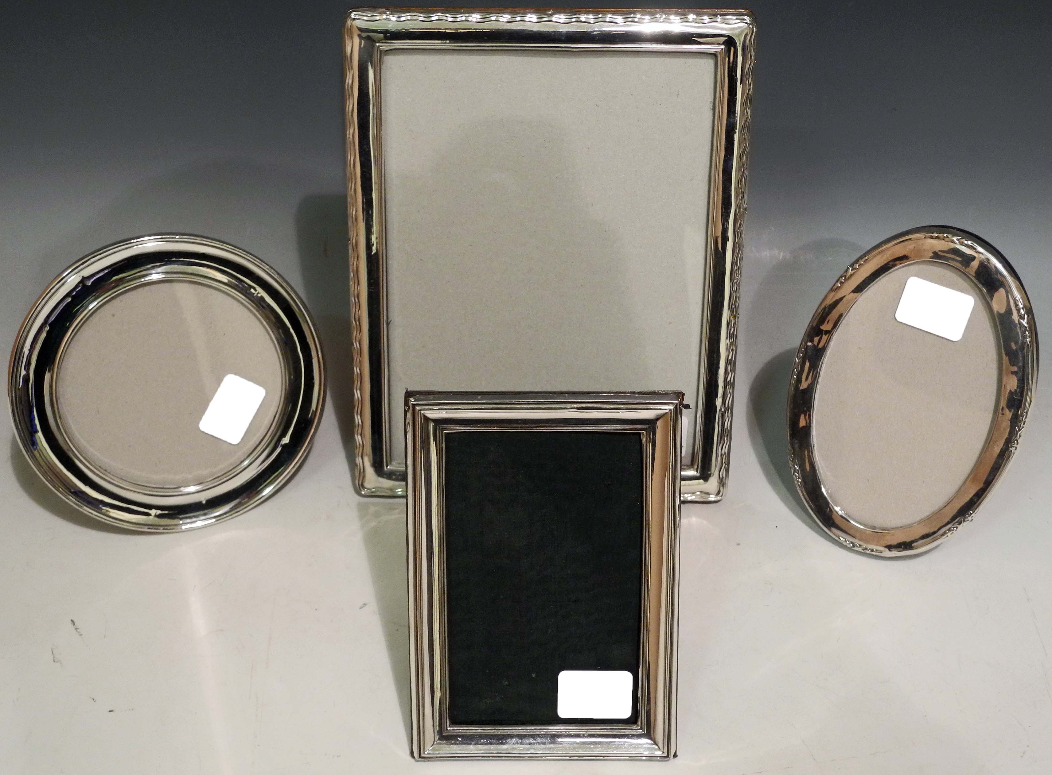 A collection of four hallmarked silver strut photo. frames to include a circular and an oval