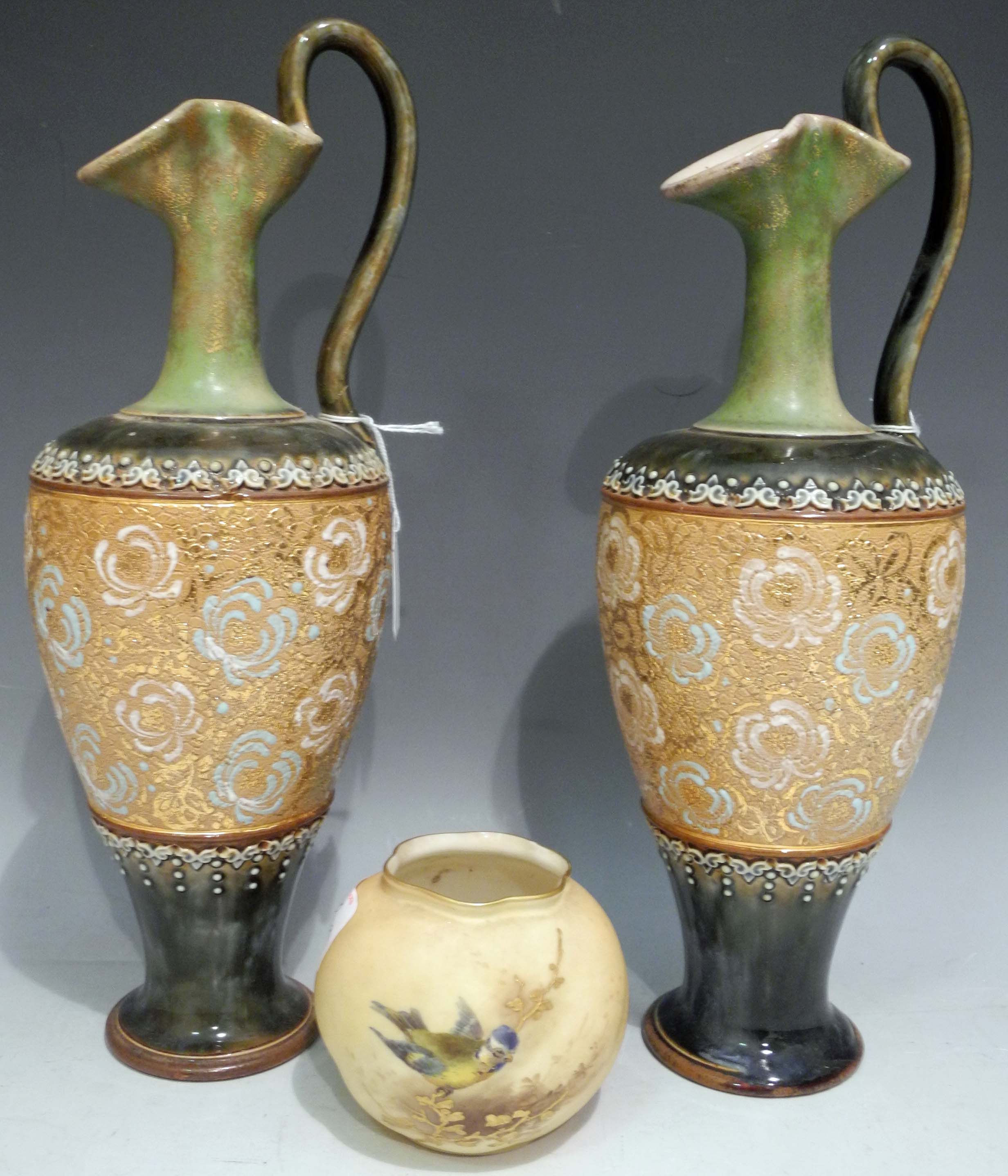 A pair of early 20th Century Royal Doulton stoneware single handled ewers, applied with foliage