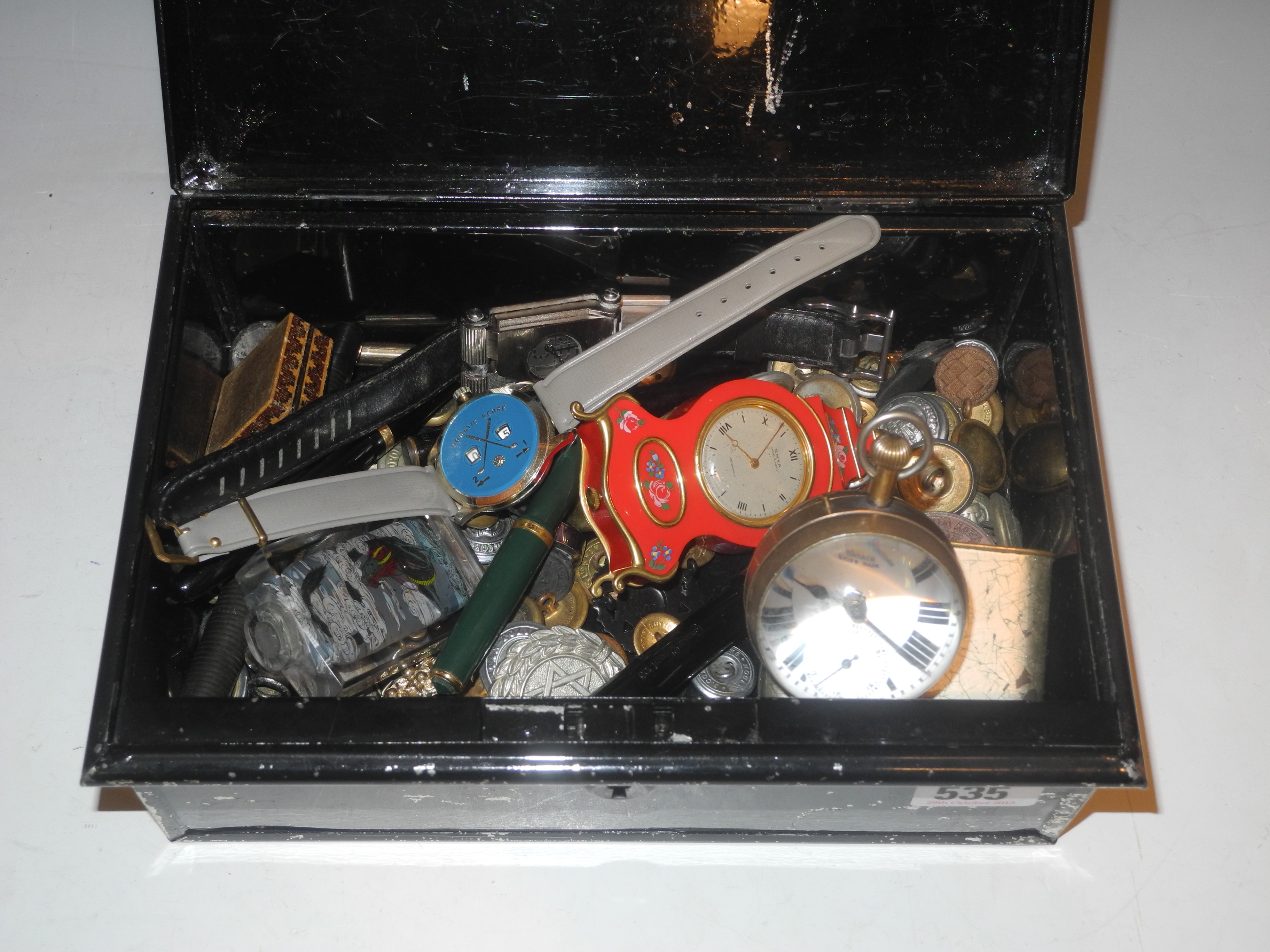 A vintage cash box containing various pens, military buttons, ball clock, watches, etc.