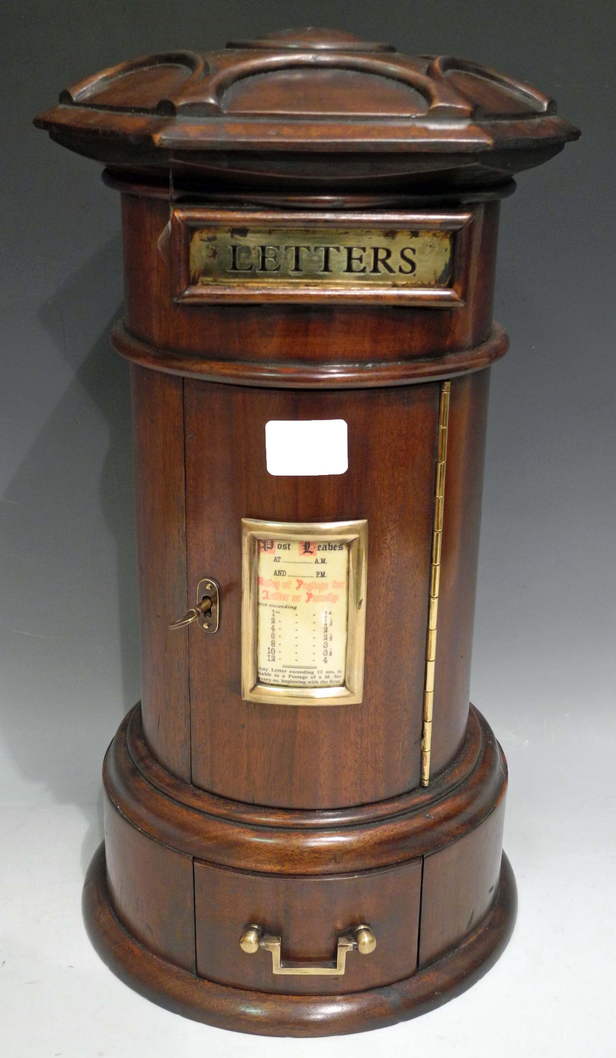 A novelty mahogany pillar box having a brass letter flap, brass framed "Rates of Postage" panel on