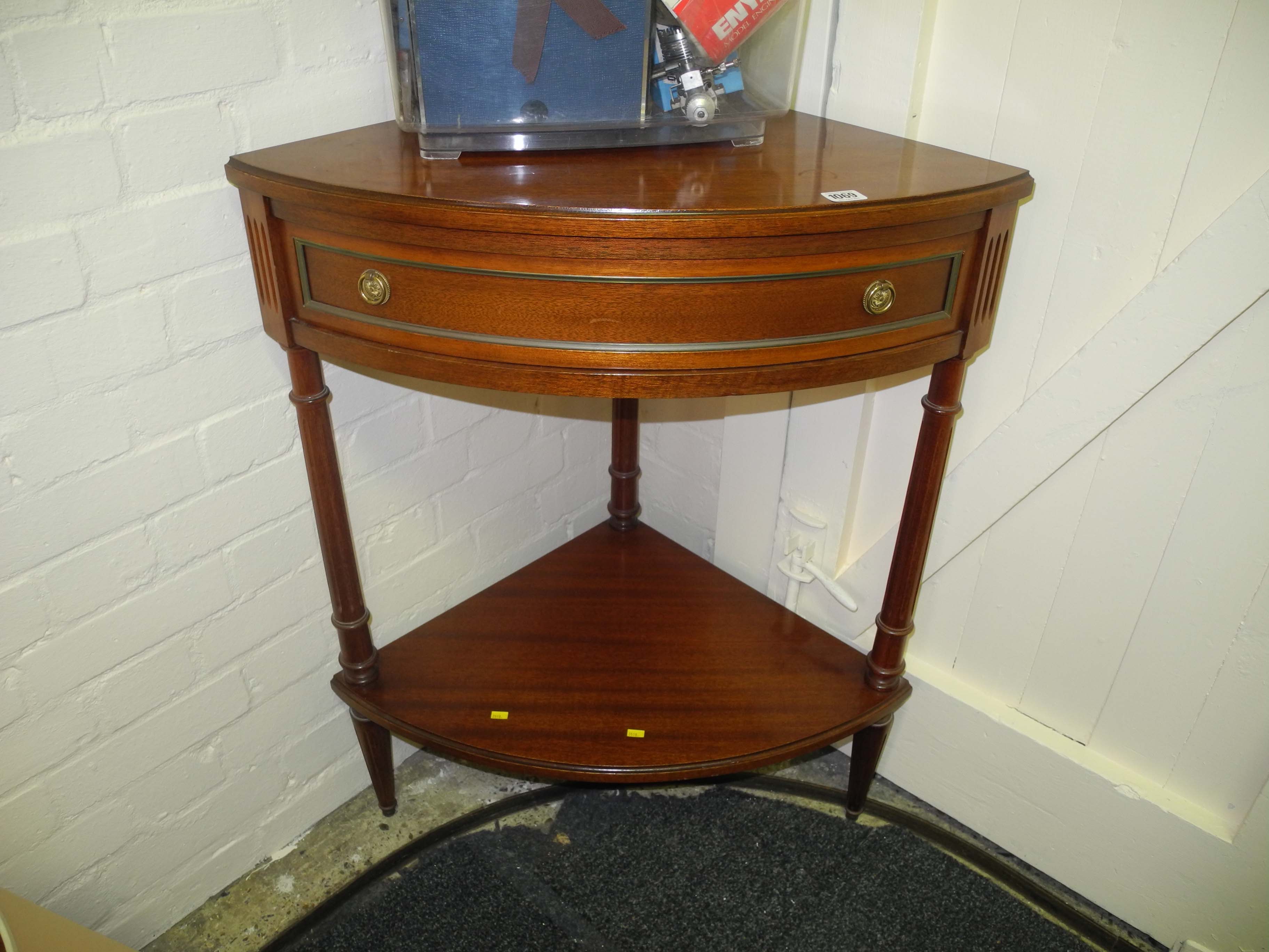 A Georgian style bow fronted corner table with frieze drawer on fluted legs joined by an undertier.