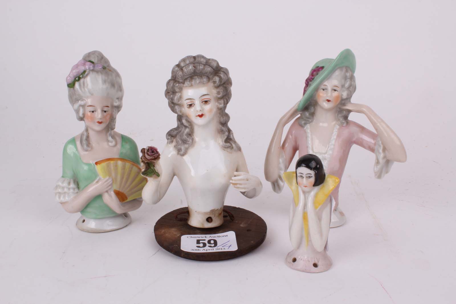 A 1920s porcelain pin cushion doll holding a rose and three other porcelain pin cushion dolls. (4).