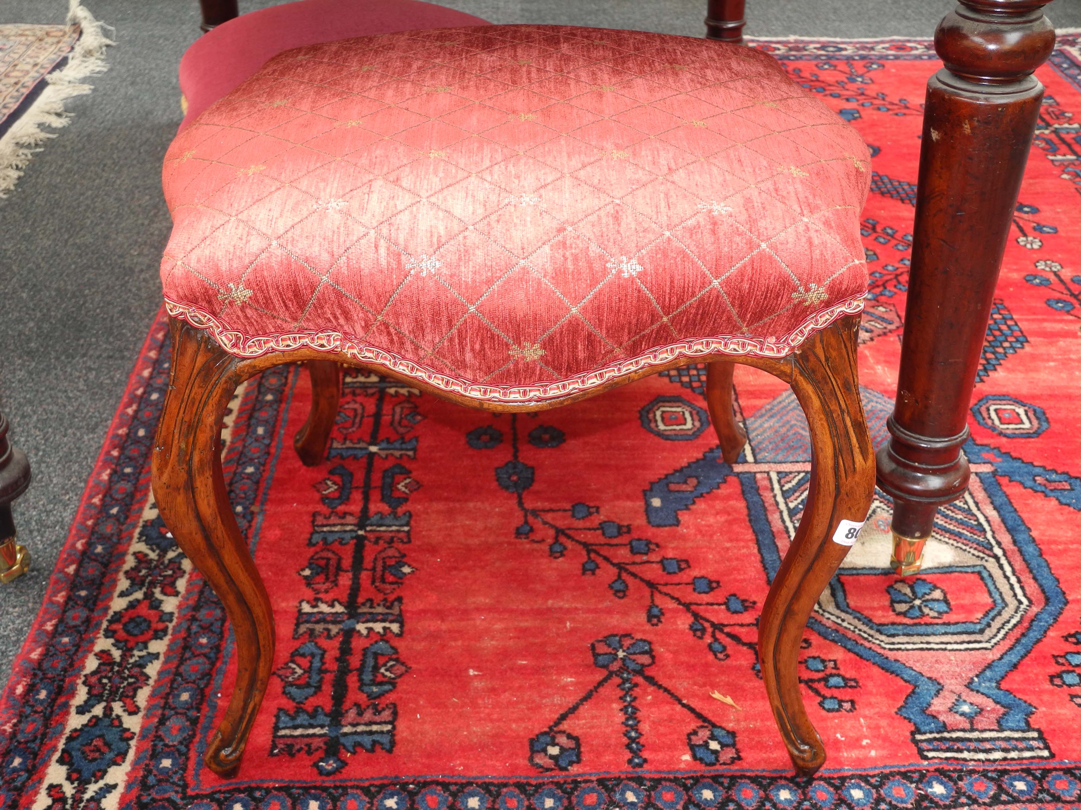 A 19th Century serpentine walnut footstool, with later overstuffed red upholstery over moulded