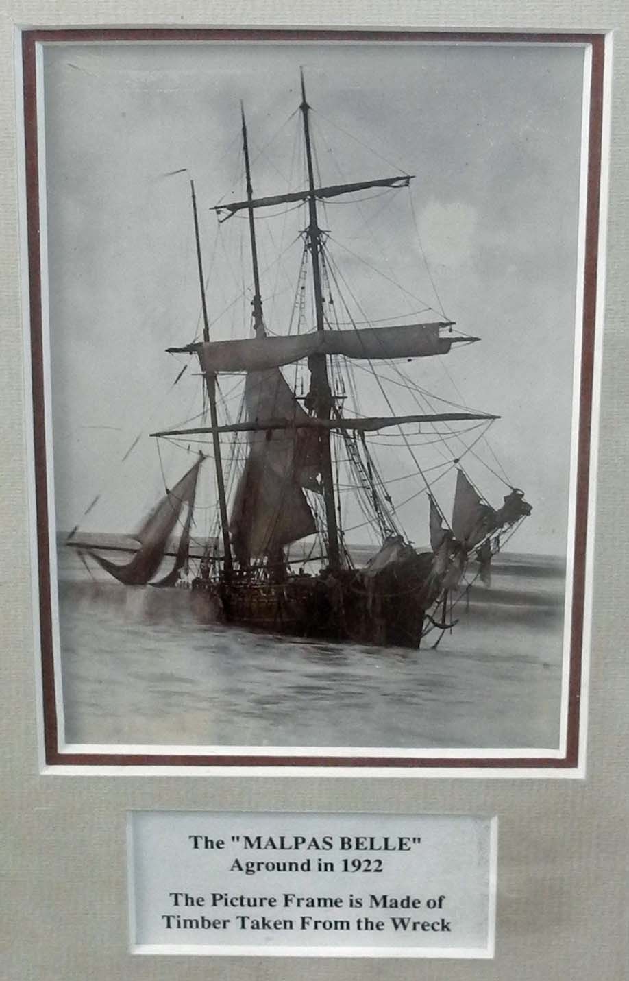 A photo. of the "Malpas Belle", in a frame in wood taken from the wreck, together with a