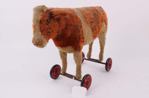 A red and cream mohair cow on red wheels, probably Steiff, German 1930s, with black boot button