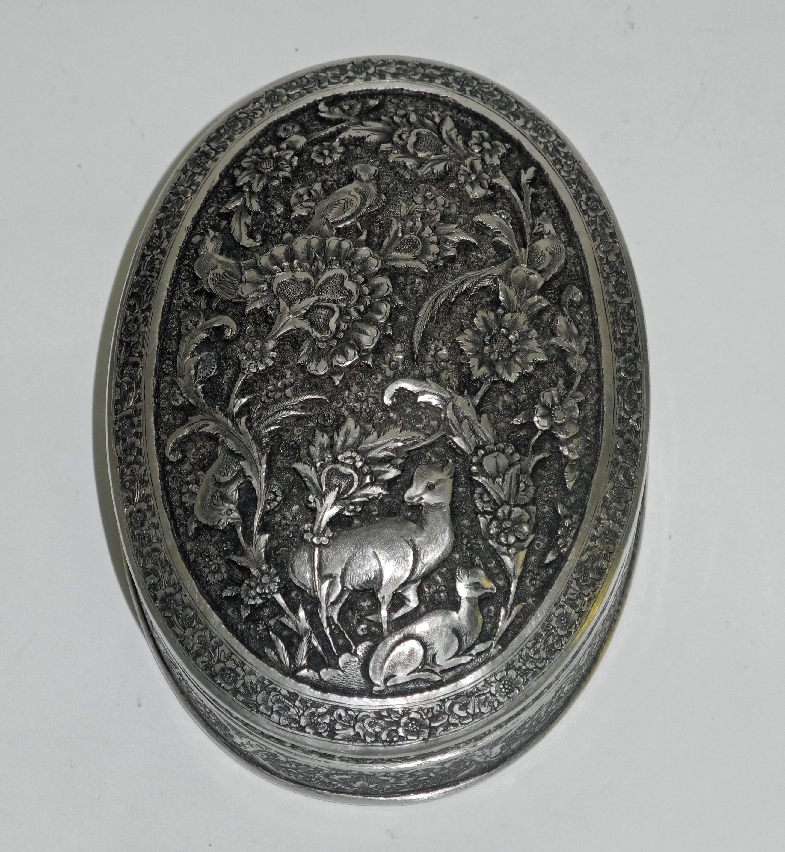 An early 20th century Persian .84 silver oval pot and cover, decorated in relief with flora and