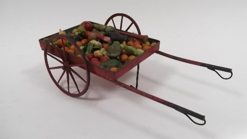 A quantity of miniature simulated fruit and vegetables and a tinplate two-wheeled cart for the same