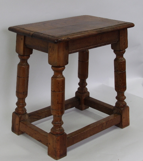 A yew wood joint stool, the planked top on turned supports united by stretchers, 42cm (16.5") wide