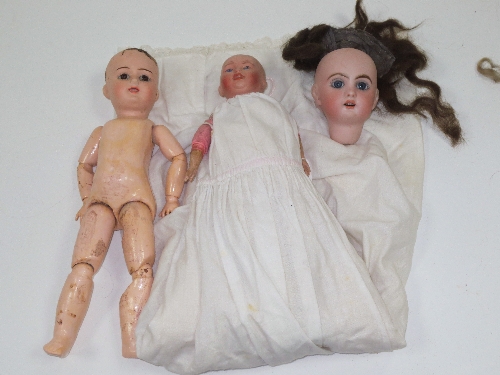 A bisque head doll with wooden lower limbs, another bisque head doll and a bisque doll's head