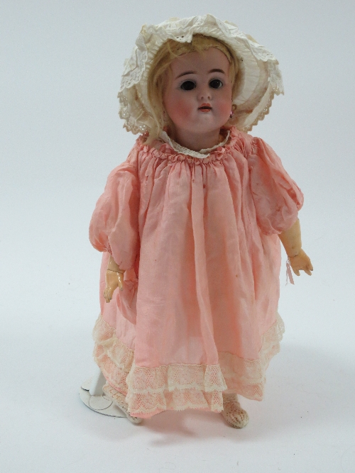 A bisque head doll with weighted eyes, open mouth, dimpled chin and pierced ears, with composition